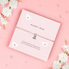 A soft pink bracelet card with a cute teddy bear charm, featuring the text 