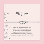 My Sister bracelet featuring two silver interlocking heart charms on an adjustable cord, presented on a blush pink card with a heartfelt message about sisterhood. Wrapped in pink tissue paper, ready for gifting. A sentimental jewellery gift for sisters, perfect for birthdays, Christmas, or just to show appreciation. A meaningful bracelet symbolising love, friendship, and connection between sisters.