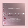 Flat lay of a “New Beginnings” bracelet gift by Letterbox Love, featuring a double silver box chain with star and bead charms, displayed on a mauve-toned sentiment card with floral illustrations and an inspiring message.