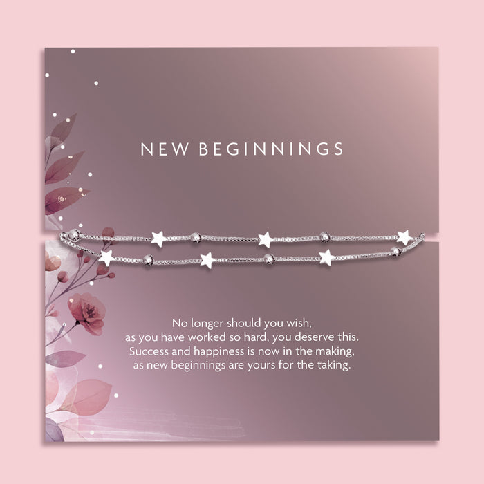 Flat lay of a “New Beginnings” bracelet gift by Letterbox Love, featuring a double silver box chain with star and bead charms, displayed on a mauve-toned sentiment card with floral illustrations and an inspiring message.