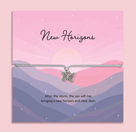 Butterfly charm bracelet on a card with 'New Horizons' text and mountain landscape design.