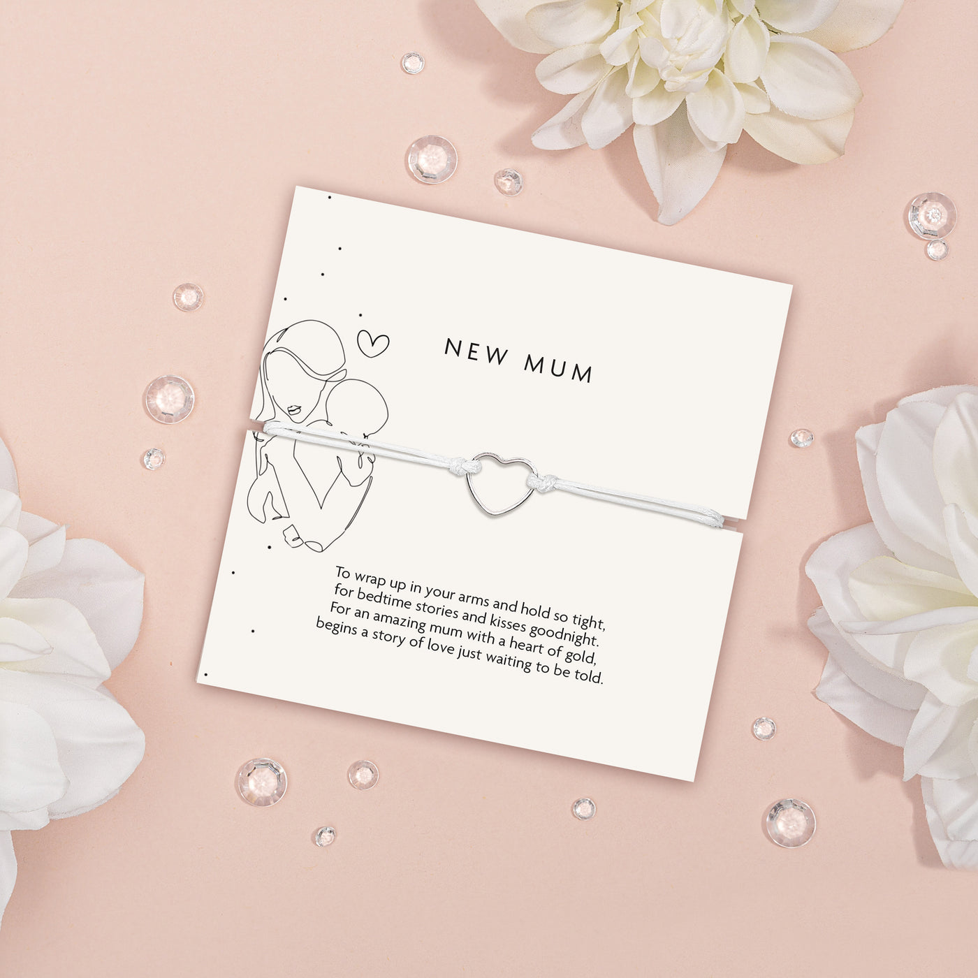 An elegant 'New Mum' bracelet with a dainty heart charm, displayed on a pastel pink background and sparkling crystals, symbolizing the gentle embrace of motherhood.