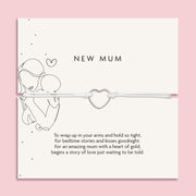 An elegant 'New Mum' bracelet with a dainty heart charm, displayed on a pastel pink background adorned with baby's breath flowers and sparkling crystals, symbolizing the gentle embrace of motherhood.