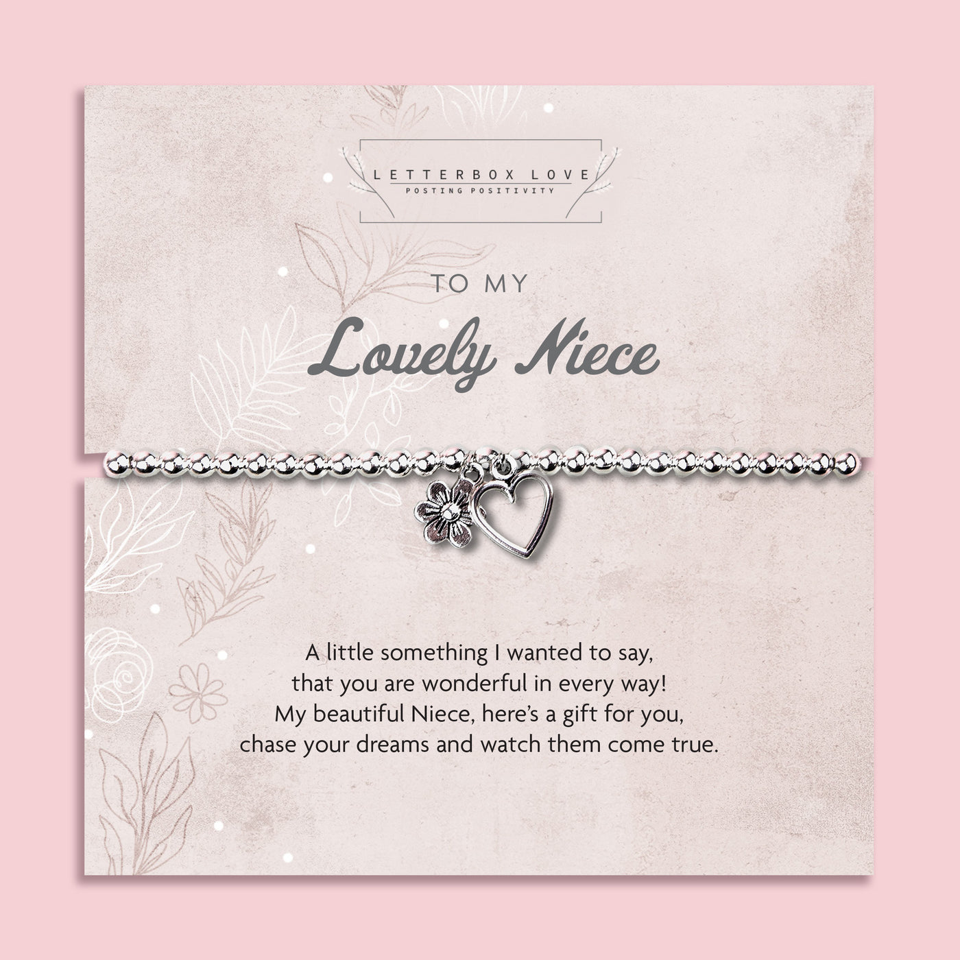 A silver beaded bracelet with a heart and flower charm displayed on a card reading 