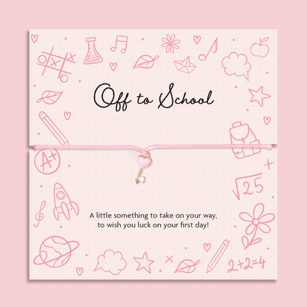 Pink cord bracelet with a rose gold heart key charm, displayed on a school-themed sentiment card reading 'Off to School ' A little something to take on your way, to wish you luck on your first day!” from Letterbox Love.