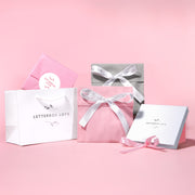 Gift boxes with ribbons and 'Letterbox Love' branding on a pink background