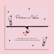 Partner in Wine bracelet featuring a red wine glass charm on a black cord, presented on a fun, illustrated card with a playful sentiment for wine lovers. A fun friendship bracelet for best friends.