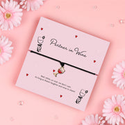 Partner in Wine bracelet featuring a red wine glass charm on a black cord, presented on a fun, illustrated card with a playful sentiment for wine lovers.