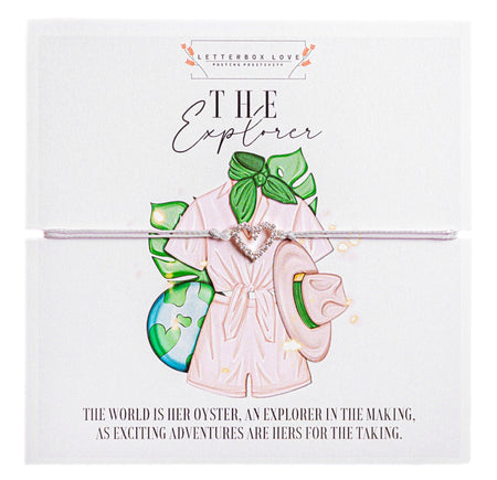Playful Explorer friendship bracelet - showcasing a playful illustration of a pink robe, a safari hat, and green tropical leaves, hinting at adventure and travel. A delicate silver bracelet with a heart-shaped charm encircles the card, symbolizing love for exploration. The card's background is white, and the text beneath the illustration states, 'The world is her oyster, an explorer in the making, as exciting adventures are hers for the taking.