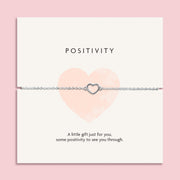 Elegant silver heart-shaped necklace on a 'POSITIVITY' card with the message 'A little gift just for you, some positivity to see you through.