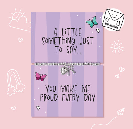 A silver beaded bracelet with a heart charm and bow pendant displayed on a lavender card that reads 'A LITTLE SOMETHING JUST TO SAY.
