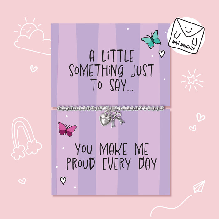A silver beaded bracelet with a heart charm and bow pendant displayed on a lavender card that reads 'A LITTLE SOMETHING JUST TO SAY.