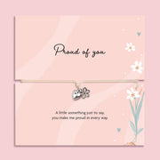 Proud of you bracelet with heart and flower charm on adjustable cord, displayed on pink sentiment card with message, encouragement gift