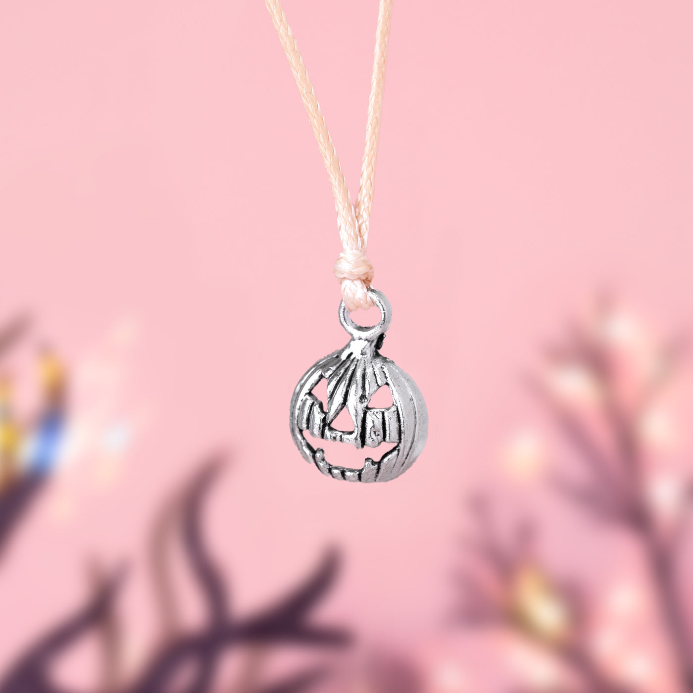 Silver pumpkin-shaped charm bracelet on a pink background, a cute charm bracelet for Autumn and Halloween