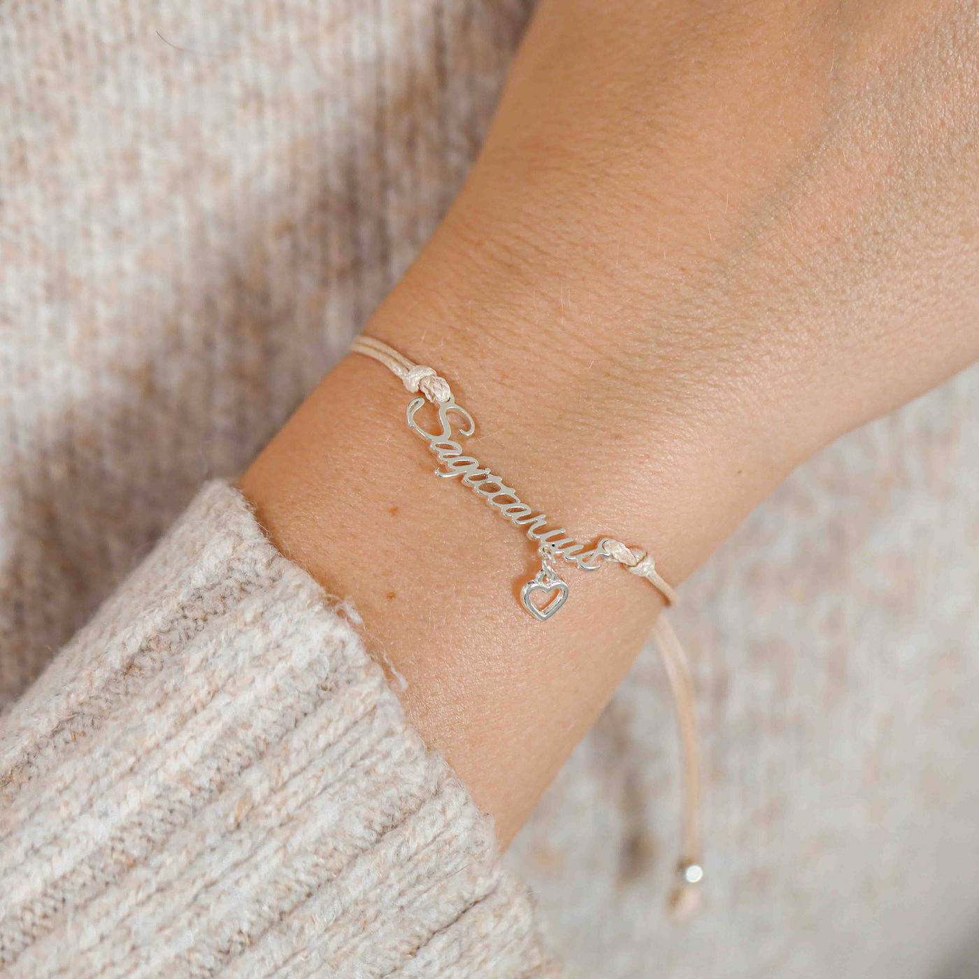 A woman wearing a dainty bracelet with the word “Sagittarius” and a tiny heart charm, a lovely zodiac-themed gift for her.