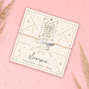 Scorpio zodiac bracelet on a matching card with decorative elements on a pink background. Scorpio bracelet for a friend
