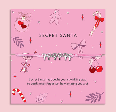 Pink Secret Santa card with decorative elements and a pink friendship bracelet on a pink background