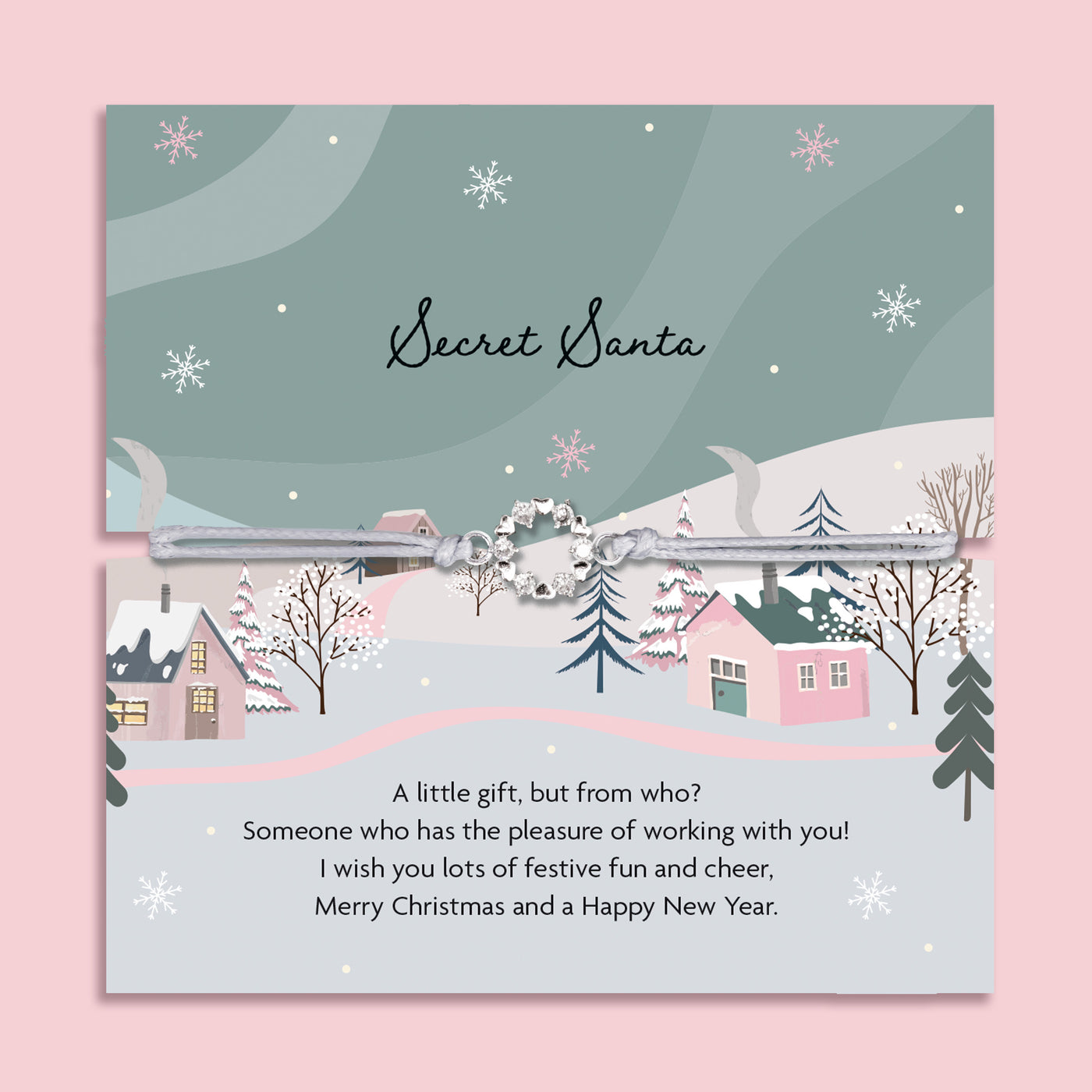 Secret Santa card with a winter village scene and festive text on a pink background, with a beautiful christmas wreath on a friendship bracelet