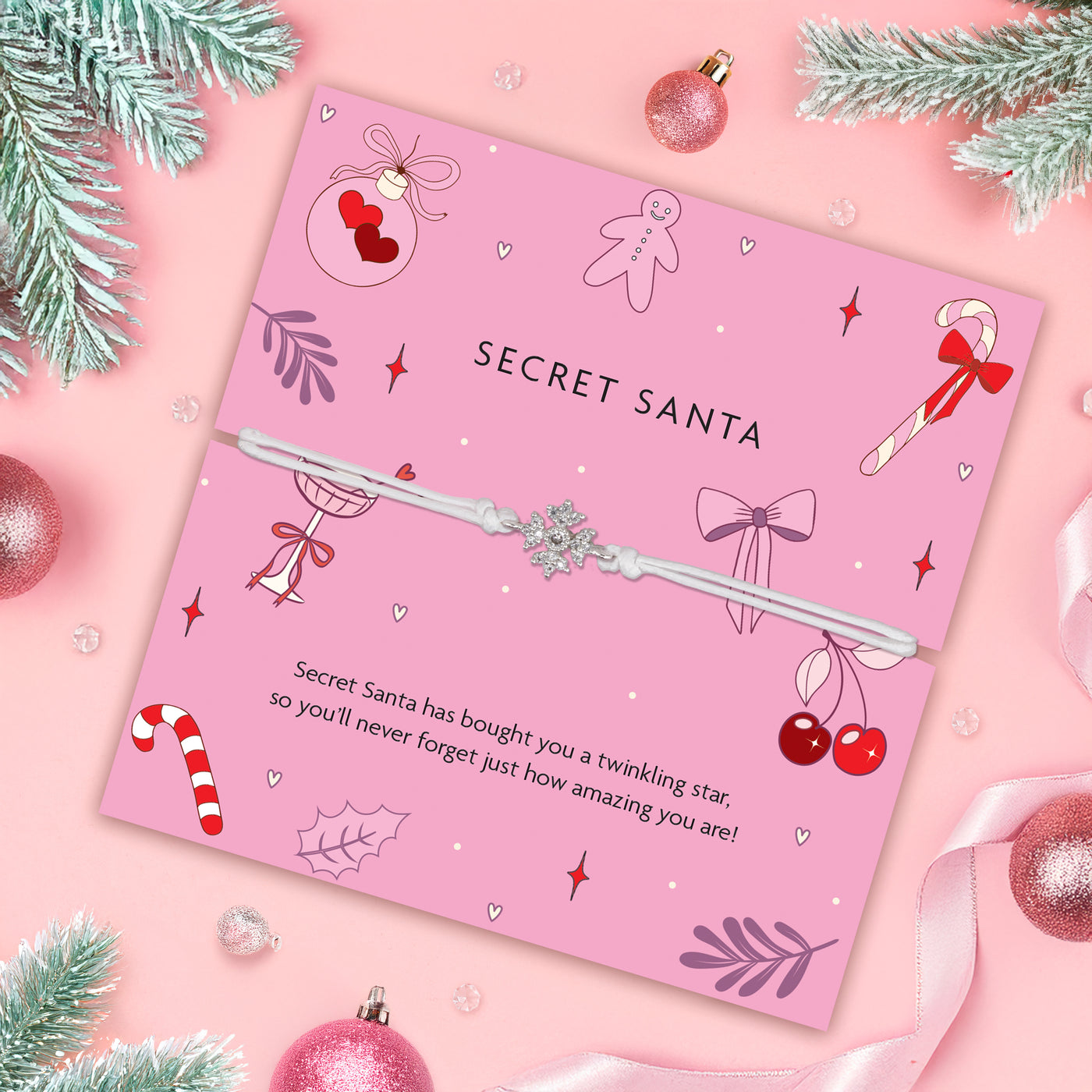 Pink 'Secret Santa' poem card with a beautiful snowflake bracelet on a pink background with Christmas decorations.