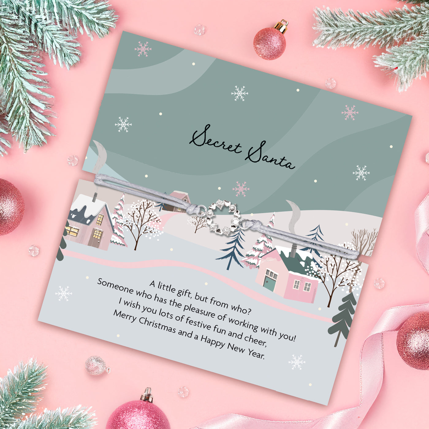 Secret Santa card with a winter scene design on a pink background with Christmas decorations, the friendship bracelet is a beautiful Xmas wreath n a grey adjustable bracelet. An ideal secret Santa gift for a colleague.