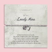 A silver beaded bracelet with a heart and flower charm displayed on a card reading "To my Lovely Nana" from Letterbox Love, set against a soft pink background. The card includes a heartfelt poem, making it a perfect sentimental gift for a Nana.