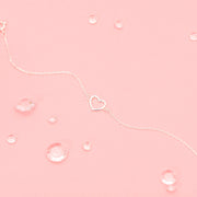 a pink background with an elegant silver heart bracelet