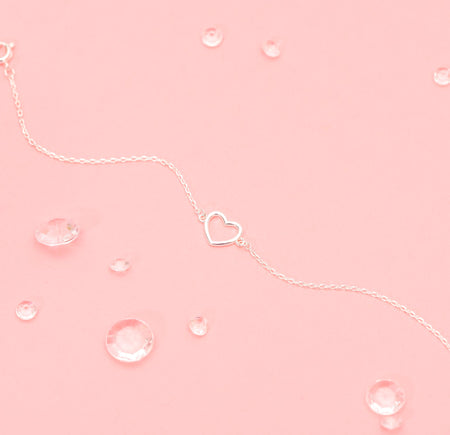a pink background with an elegant silver heart bracelet