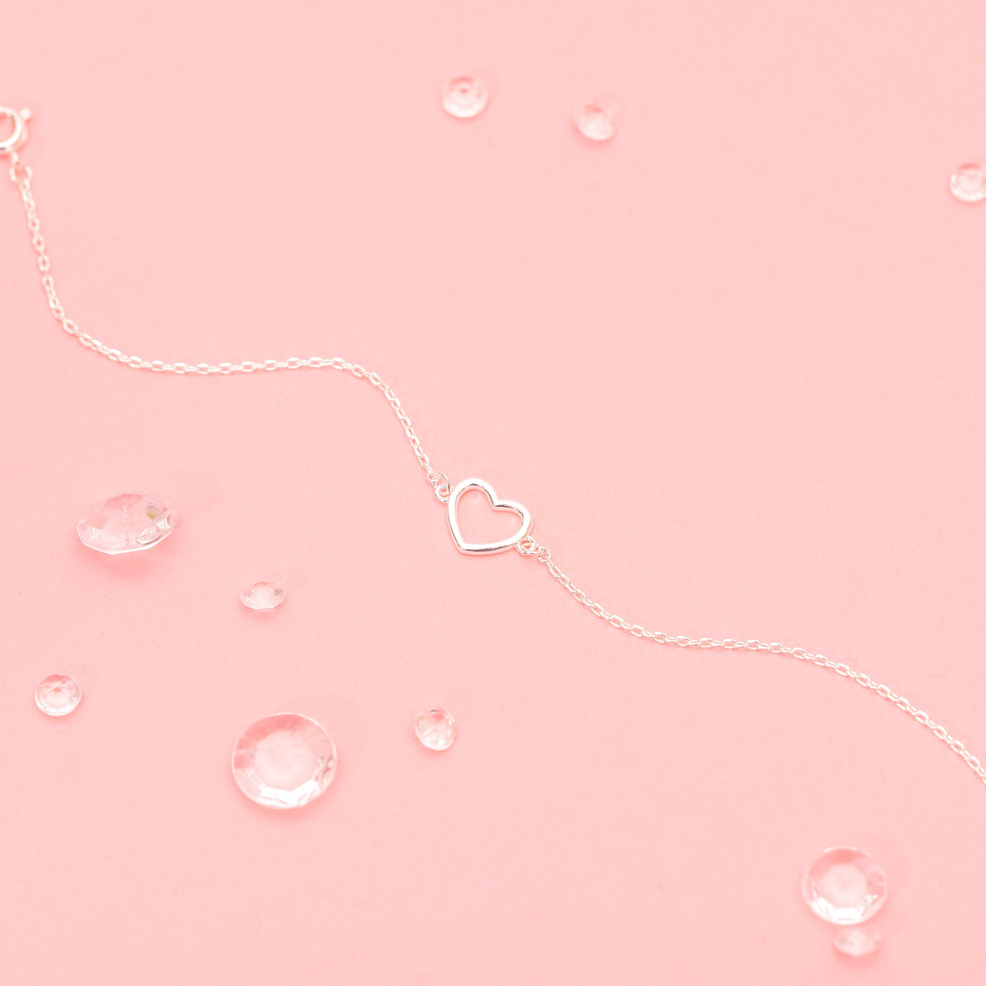 a pink background with an elegant silver heart bracelet