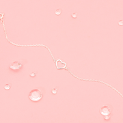 A pink background with small gem stones and a silver-plated hollow heart bracelet. An elegant gift for a bridesmaid to say thank you.