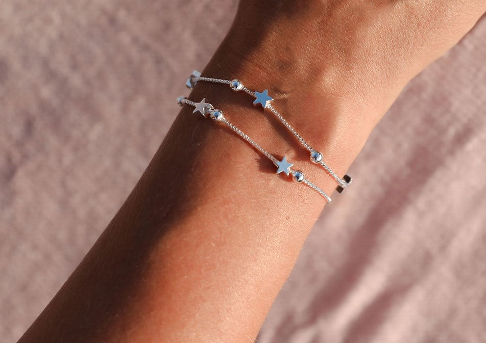 A woman with a star bracelet. Close-up angle of her arm with the dainty silver star bracelet.
