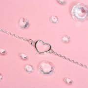Pretty silver detail bracelet on a pink background surrounded by gems. The bracelet is dainty making an elegant leaving gift for a colleague