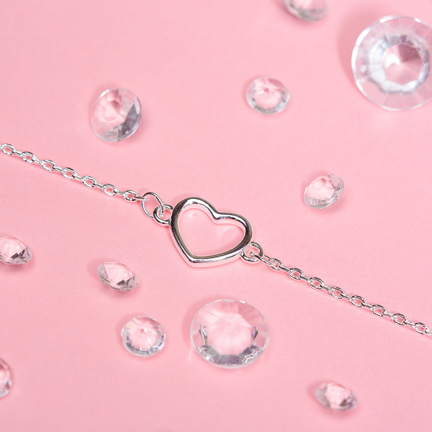 Pretty silver detail bracelet on a pink background surrounded by gems. The bracelet is dainty making an elegant leaving gift for a colleague