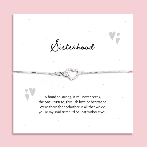 Silver-plated adjustable bracelet with an infinity heart charm, displayed on a white sentiment card titled "Sisterhood" with a heartfelt poem about soul sisters. Styled on a soft pink background with subtle heart and dot details.