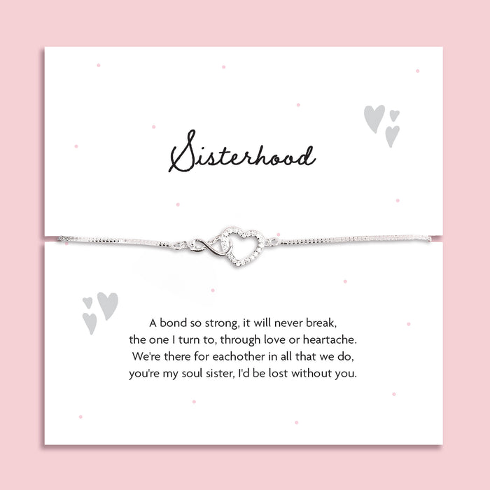 Silver-plated adjustable bracelet with an infinity heart charm, displayed on a white sentiment card titled "Sisterhood" with a heartfelt poem about soul sisters. Styled on a soft pink background with subtle heart and dot details.