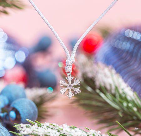 A festive background with a detailed photo of a snowflake bracelet charm