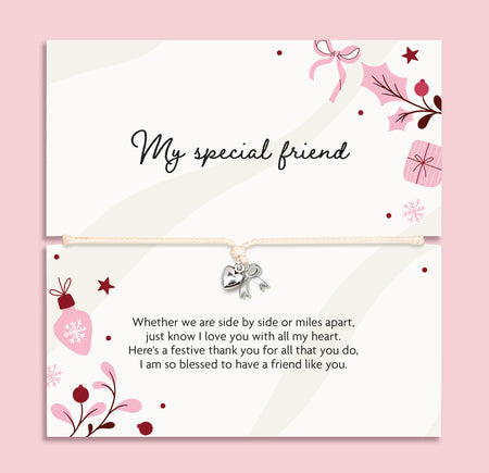 A friendship bracelet featuring a cream card with elegant black script reading 'My special friend' and a matching poem on the bottom, with a bracelet with a small silver heart charm and bow. The cards are decorated with pink and burgundy floral illustrations, set against a solid pink background.