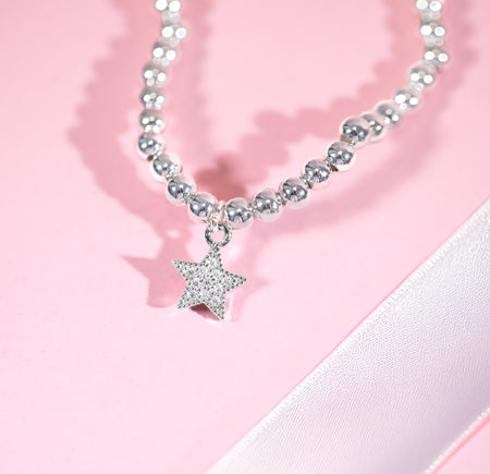 Bracelet with a star-shaped charm on a pink background