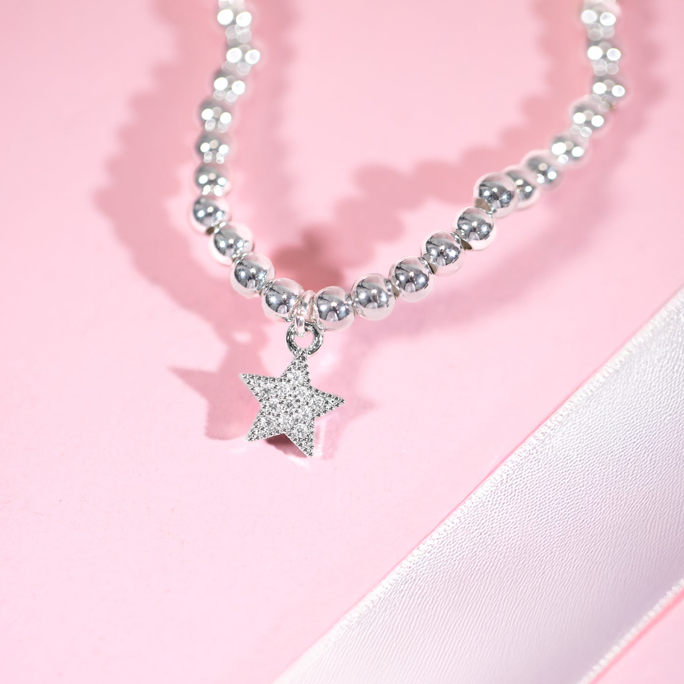 Bracelet with a star-shaped charm on a pink background