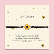 Adjustable black cord bracelet with a yellow sunflower charm, displayed on a cream card titled 'Sunflower'. The card features a cheerful poem about brightness, growth, and sunshine. Surrounded by flowers on a pink background, this is a joyful gift from Letterbox Love.