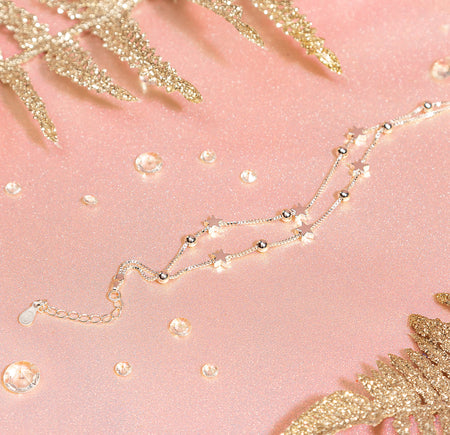 A sparkly pink background with sparkly leaves, in the centre is the Sweet 16 silver-plated star bracelet surrounded by gems. A heartfelt gift for a 16th birthday. 