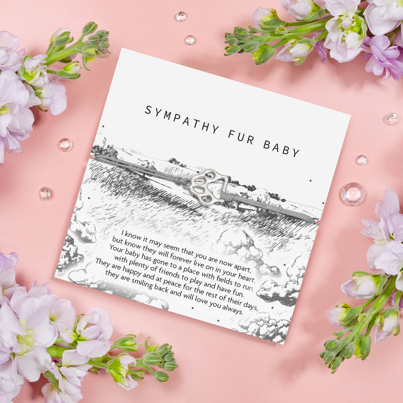 A heartfelt sympathy card titled 'Sympathy Fur Baby' surrounded by soft grey clouds and field.  The card features a touching message of remembrance and a delicate silver paw print charm.