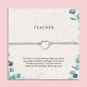 A thoughtful gift card titled "TEACHER" featuring a heartfelt appreciation note for a teacher, accompanied by a simple yet elegant bracelet with a heart-shaped charm. The card's design includes subtle green foliage patterns on a soft grey background, creating a calm and appreciative atmosphere suitable for expressing gratitude to educators.