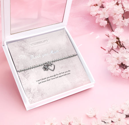 Silver beaded bracelet with heart and flower charms, presented in a white gift box alongside a card titled 