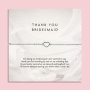 Silver bracelet with heart charm on a thank you card for a bridesmaid, on a pink background. A meaningful gift for a bridal party, silver jewellery to say thank you to a bridesmaid.