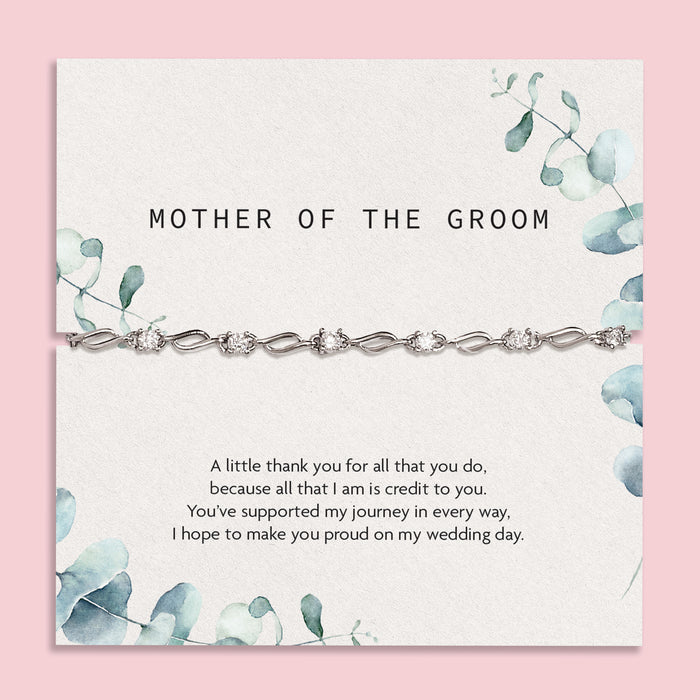 Elegant 'Mother of the Groom' card set against a silky white fabric backdrop. The card, adorned with soft blue floral designs, expresses gratitude and appreciation with a heartfelt message. Draped over the card is a sophisticated silver bracelet with intricate detailing. 