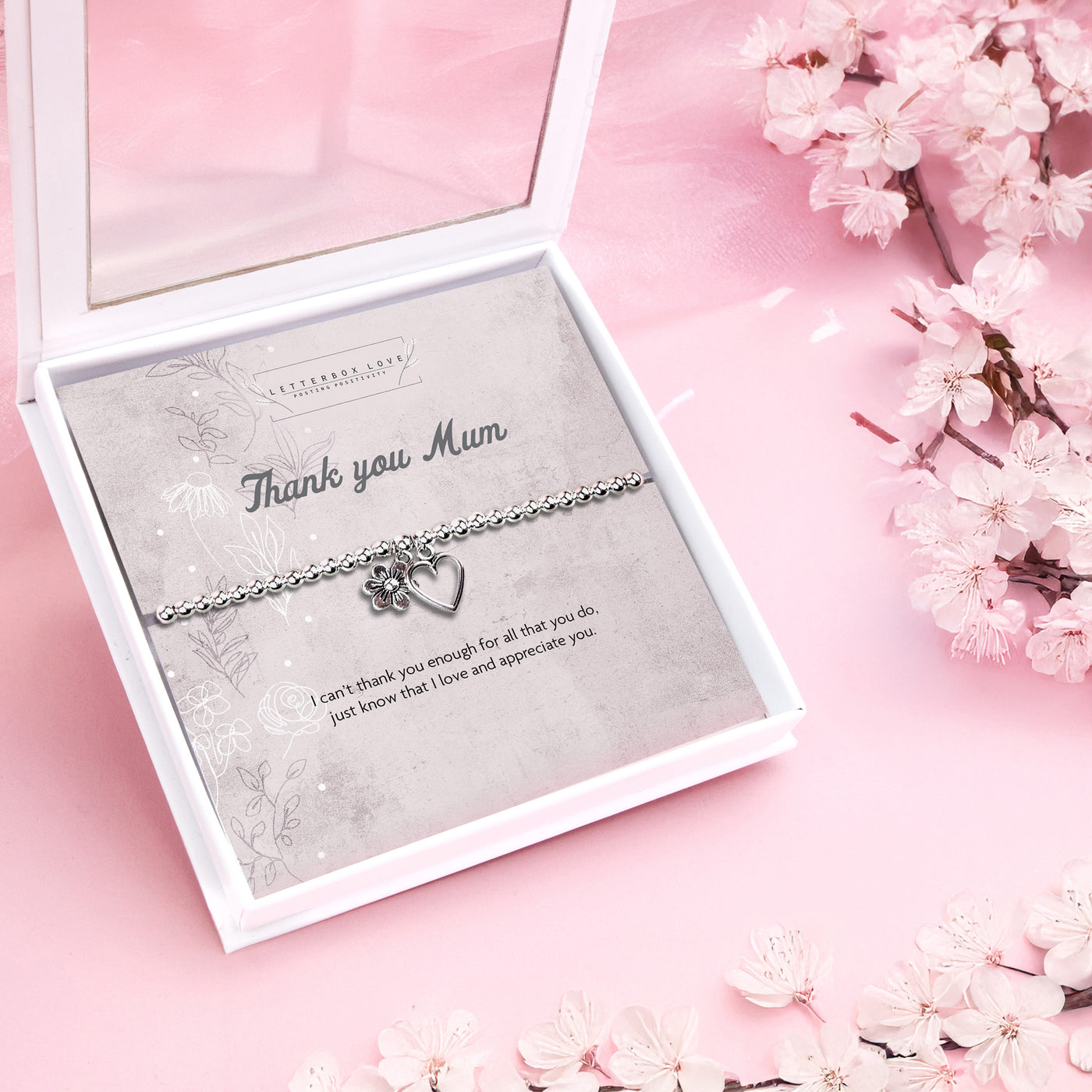 Silver beaded bracelet with heart and flower charms, presented in a white gift box alongside a card titled 