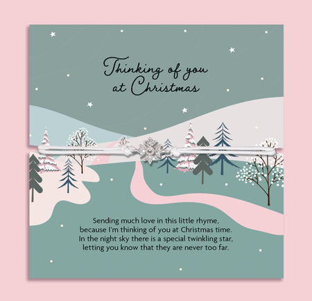 Thinking of You at Christmas bracelet featuring a sparkling cubic zirconia snowflake charm on an adjustable cord, presented on a festive winter card with snowy trees, stars, and heartfelt poem. Includes a soft white pouch for gifting and safekeeping. A sentimental Christmas jewellery gift, perfect for friends, family, or loved ones. Ideal as a stocking filler, memorial keepsake, or thoughtful way to show love and remembrance during the holiday season.