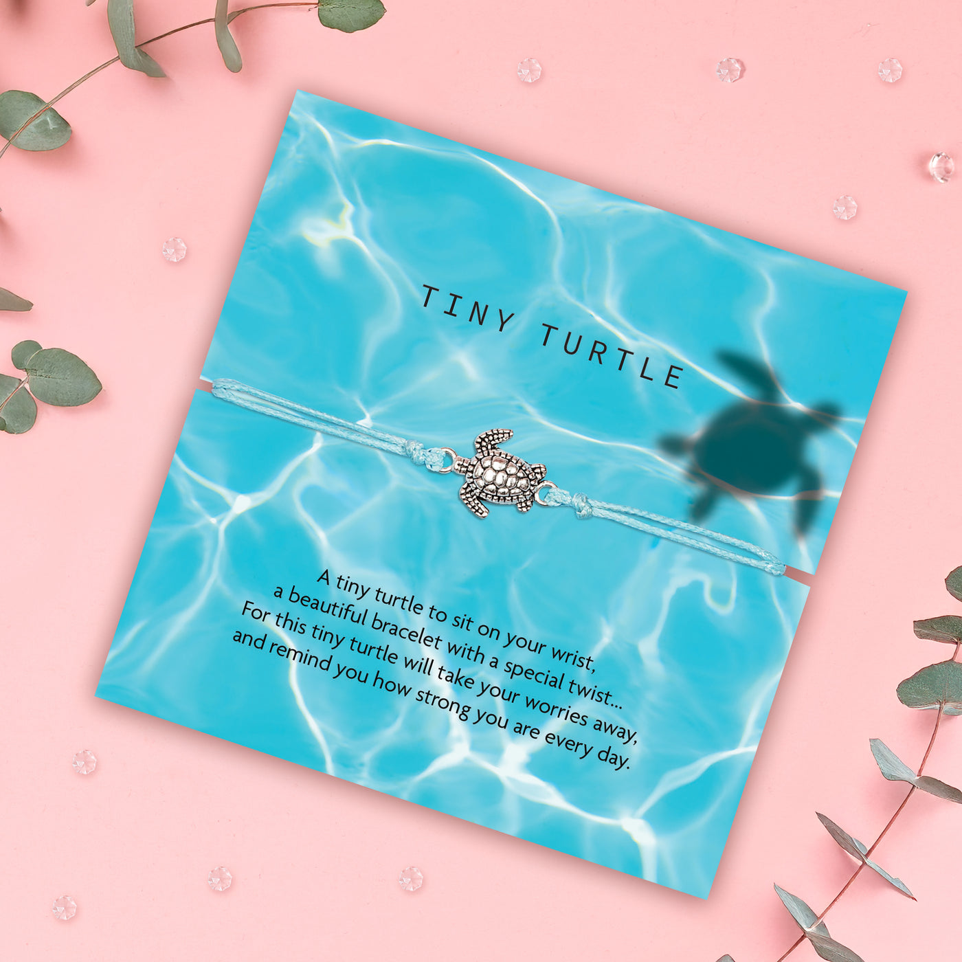 A turquoise bracelet with a small silver turtle charm, displayed on a card with a water-themed background. The card reads: 'Tiny Turtle. A tiny turtle to sit on your wrist, a beautiful bracelet with a special twist... For this tiny turtle will take your worries away and remind you how strong you are every day.' At the top, the brand name 'Letterbox Love' is shown with the tagline 'Posting Positivity