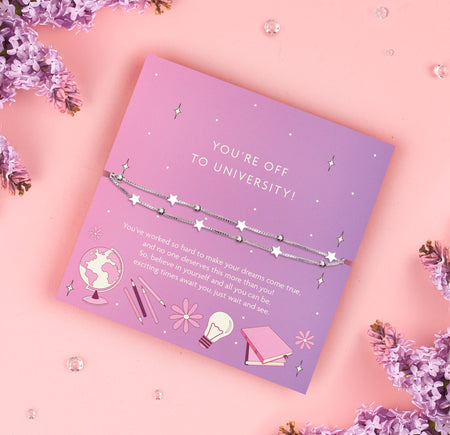 
A delicate double-layer silver bracelet featuring star charms and beads, displayed on a lilac backing card with the message 