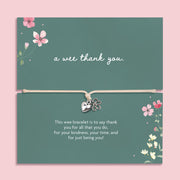 Silver heart and flower charm bracelet on an adjustable cord displayed on a green floral card featuring the Scottish phrase “a wee thank you”. Meaningful thank you gift for friends, teachers, coworkers or loved ones.